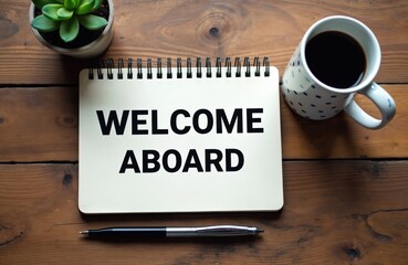 Notebook with WELCOME ABOARD text on wooden desk with coffee and plant. Pen nearby suggests writing notes for new hire or guest. Business welcome message.
