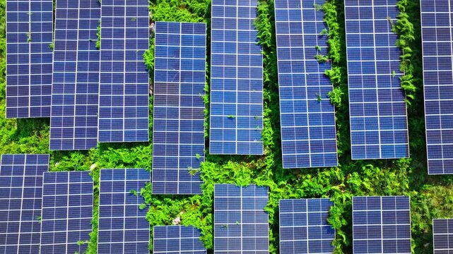 Aerial shot of solar power station generating clean energy on green mountain slopes