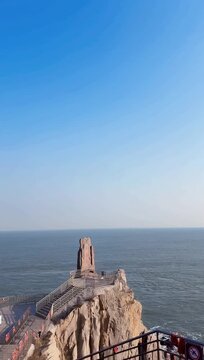 Scenic vertical footage of the famous Chengshantou scenic spot in Rongcheng, Weihai, Shandong province, China. A stone monument with Chinese calligraphy stands on a rocky cliff overlooking the blue oc