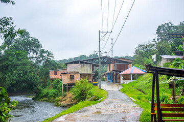 Obraz premium A tranquil street in San Cipriano, Buenaventura, Valle del Cauca, showcasing lush nature and local architecture amid serene surroundings.