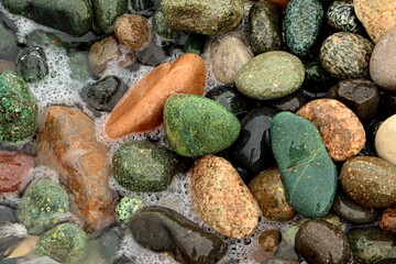 Background, texture of sea pebbles in the sea foam of the surf