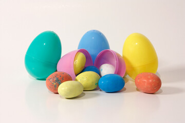 An open plastic Easter egg filled with some chocolate eggs against a white background