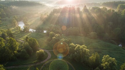Golden sunlight breaks through the morning mist over a lush green valley landscape