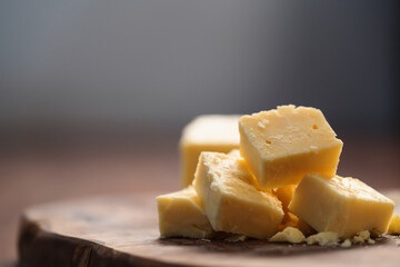 White cheddar cheese pieces on olive wood board