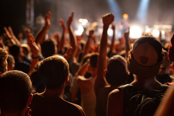 crowd of people cheering music band at concert, unrecognizable people with raised hands