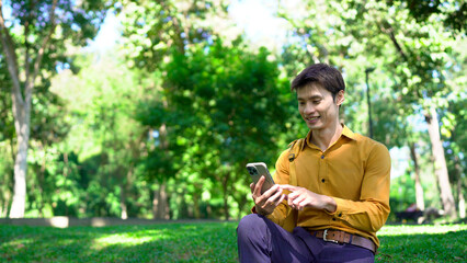 Young asian businessman using smartphone outdoors in park