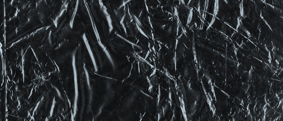 Wrinkled plastic wrap texture on a black background. Cellophane package wallpaper