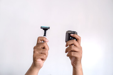 A pair of hands holding two different razors,manual razor vs electric shaver comparison on white background, men's grooming concept.