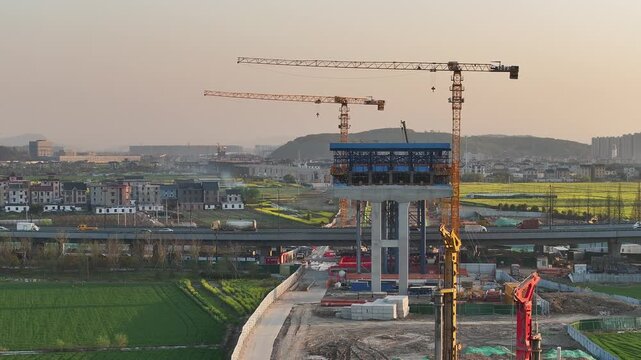 High-speed rail bridge pier construction site with multiple cranes at dusk