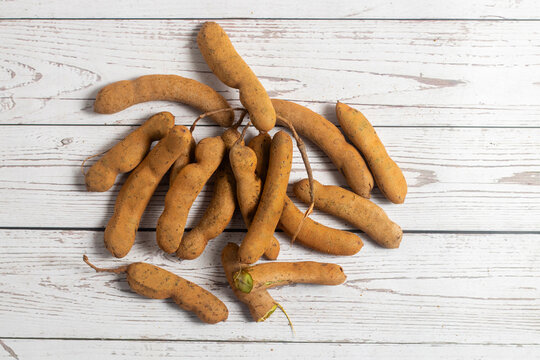 Tamarind is a tangy-sweet tropical fruit with sticky pulp, used in chutneys, curries, drinks, and candies worldwide for flavor enhancement
