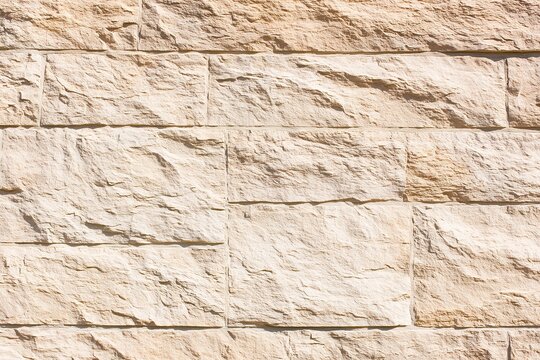 Textured, beige, stone wall with rectangular block pattern