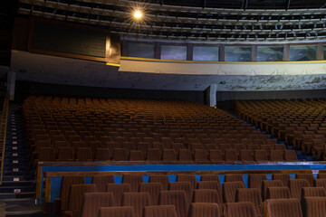Abandoned concert hall auditorium in Tallinn City Hall, showing rows of empty brown chairs, atmospheric urban decay photography of a forgotten Estonian cultural entertainment venue
