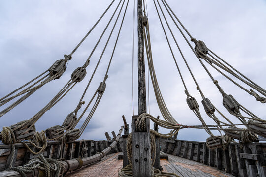 Close-up of Antique Sailing Ship Mast and Intricate Rigging Detail against Dark Overcast Sky, Representing History, Travel, and Nautical Heritage.