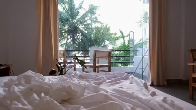 Beautiful hotel room interior with a balcony overlooking palm trees and the indian Ocean. Bright tropical resort accommodation, luxury travel lifestyle, relaxing vacation atmosphere and ocean view. 