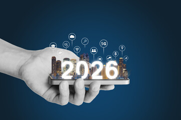 2026 new smart technology, IOT technology. Hand holding mobile smartphone with building and 2026 hologram