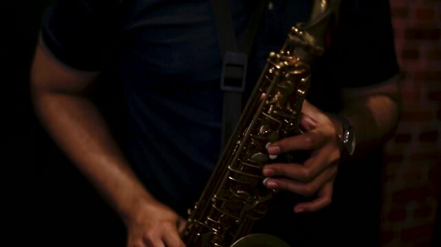 A detailed close-up of a male musician&rsquo;s hand playing a golden saxophone during a jazz rehearsal. The image captures the warmth of brass tones and the texture of the instrument, highlighting passion, 