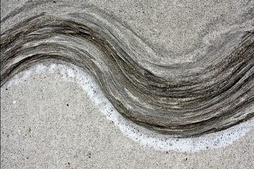 Obraz premium Sand swirl wave pattern near water's edge, textured, slightly grainy