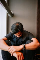 Depressed Young Man Sitting Alone with Head Down