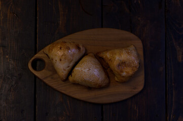 three meat pies on a wooden cutting board