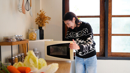 side view of smiling woman in shirt using microwave in kitchen