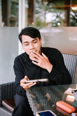 Casual Break: Young Man Smokes Cigarette and Checks Phone