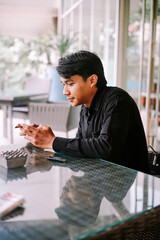 Young Man Smoking and Using Smartphone at Outdoor Cafe