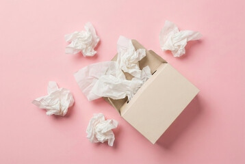Open cardboard box with crumpled white tissue paper scattered on pink background, minimal packaging and waste concept