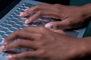 A person's hands are typing on a laptop keyboard.