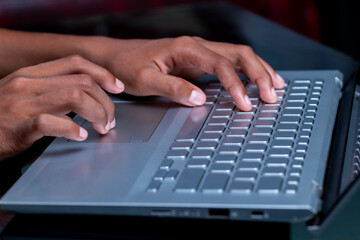 A person's hands are typing on a laptop keyboard.