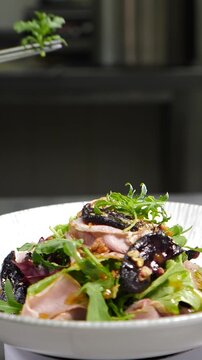 Final touch in dish serving. Cooking process. Luxury restaurant. Chef finishing duck dish with salad leaf. Serving plate with micro greens. final ingredients. restaurant kitchen. Vertical 4 k video