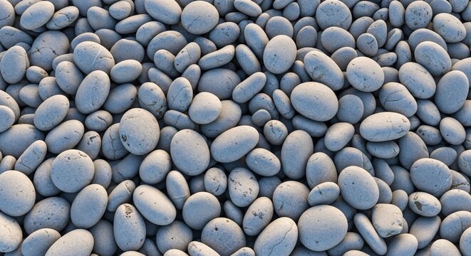 Close-up of smooth rounded pebbles and stones on a natural beach surface with soft shadows and subtle color variations for a tranquil coastal scene