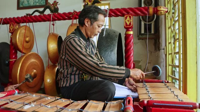 Indonesian musician playing traditional gamelan saron