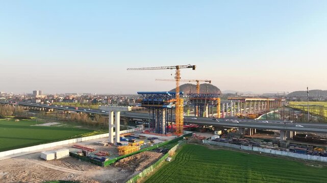 High-speed railway station under construction with crane and elevated bridge in progress