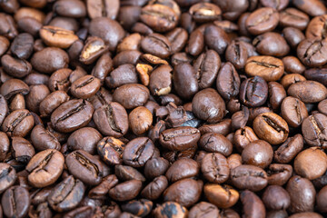 Fototapeta premium Shiny coffee beans, Aromatic roasted coffee closeup, Glistening roasted beans with textured surface, Warm brown roasted beans displaying oil and surface details