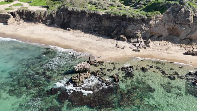 Aerial Drone Side Flight Past Ancient Ruins and Fishermen on Rocky Beach