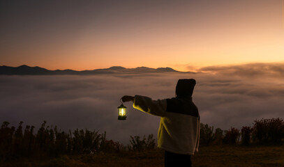 A new morning, mountains sea of ​​fog a woman holds a lantern to illuminate the night