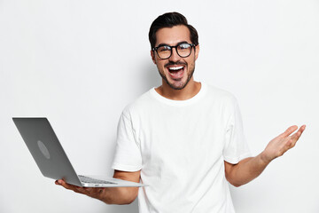 Full body smiling young caucasian man wear casual white t-shirt look at camera hold in hand modern laptop cheerful expression isolated on plain solid light background.
