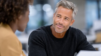 Caucasian mature male and african adult female conversing in office setting