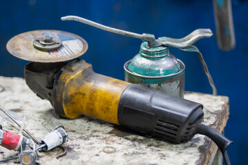 Close-up of a dirty, yellow and black electric angle grinder with a worn cutting disc (grinding...