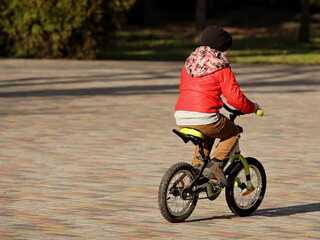 A boy rides a bicycle in the park on a sunny spring day. Children's activity for the harmonious development of the teenage generation. Game in the fresh air. Equilibrium on a two-wheeled transport