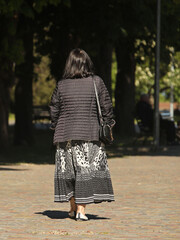 A woman is walking in the park with a man who is traveling on an electric wheelchair. Custody of the needy. The activity of people with limited mobility. Prosthetics of patients of the musculoskeletal
