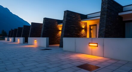 Modern resort buildings with warm exterior lights, stone facades, and paved walkway at twilight