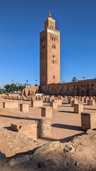 Fototapeta premium Koutoubia-Moschee in Marrakesch: Das markante Minarett aus rötlichem Sandstein erhebt sich vor tiefblauem Himmel über die historische Altstadt. 