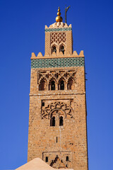 Obraz premium Koutoubia-Moschee in Marrakesch: Das markante Minarett aus rötlichem Sandstein erhebt sich vor tiefblauem Himmel über die historische Altstadt. 