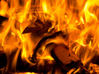 Close-up eines brennenden Haufens Holz, mit gl&uuml;henden Holzscheiten und orange z&uuml;ngelnden, hei&szlig;en Flammen in einem Brennofen