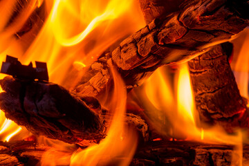 Close-up eines brennenden Haufens Holz, mit gl&uuml;henden Holzscheiten und orange z&uuml;ngelnden, hei&szlig;en Flammen in einem Brennofen