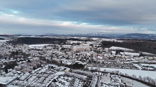Luftaufnahme von St. Florian bei Linz mit schneebedeckten Feldern und Wohngebieten. Luftaufnahme von St. Florian bei Linz mit schneebedeckten Feldern und Wohngebieten. Dunkle Wolkenfelder kontrastiere