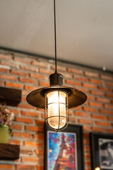 A classic style ceiling lighting lamp with iron cage during it glowing in warmlight shade. Interior object, close-up with selective focus.