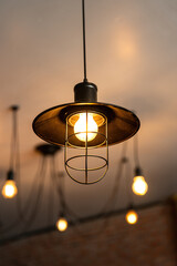 A classic style ceiling lighting lamp with iron cage during it glowing in warmlight shade. Interior object, close-up with selective focus.