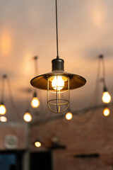 A classic style ceiling lighting lamp with iron cage during it glowing in warmlight shade. Interior object, close-up with selective focus.